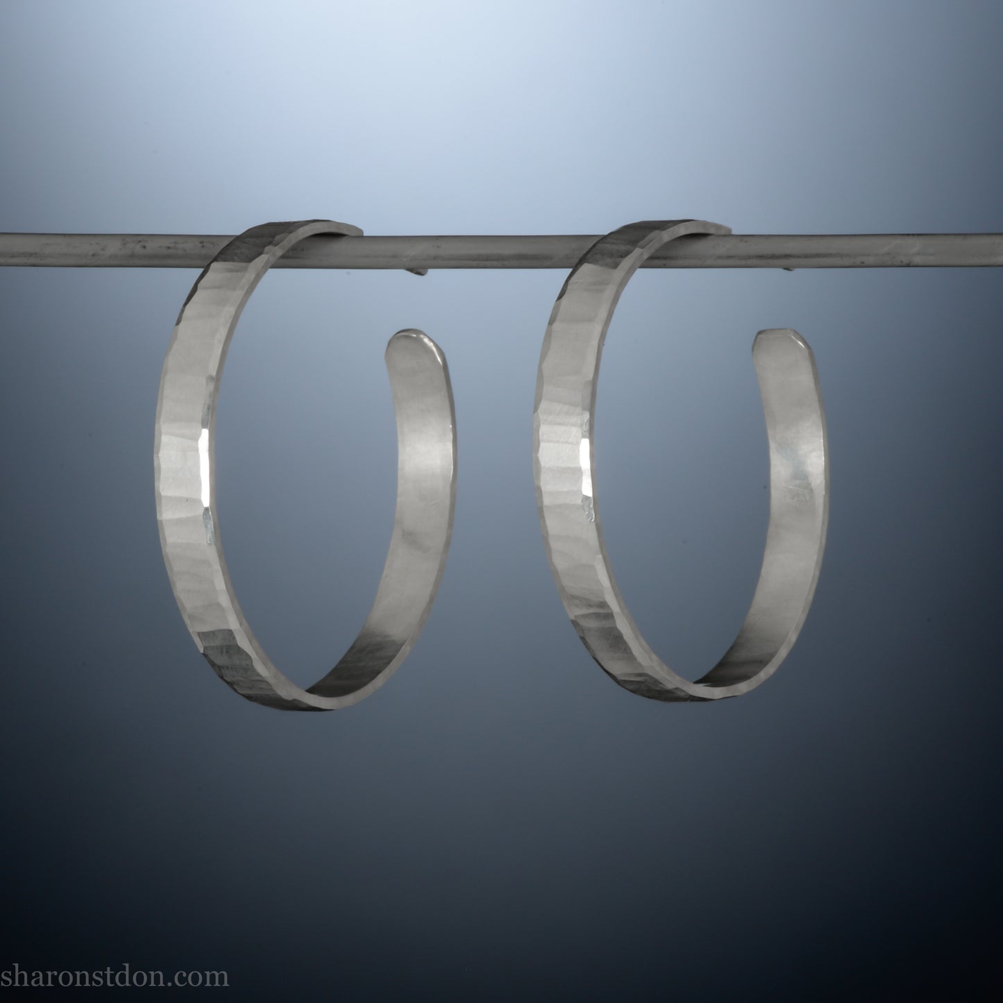 Hand hammered solid sterling silver hoop earrings with faceted, wavy texture and matte satin finish, 30 mm x 4 mm.