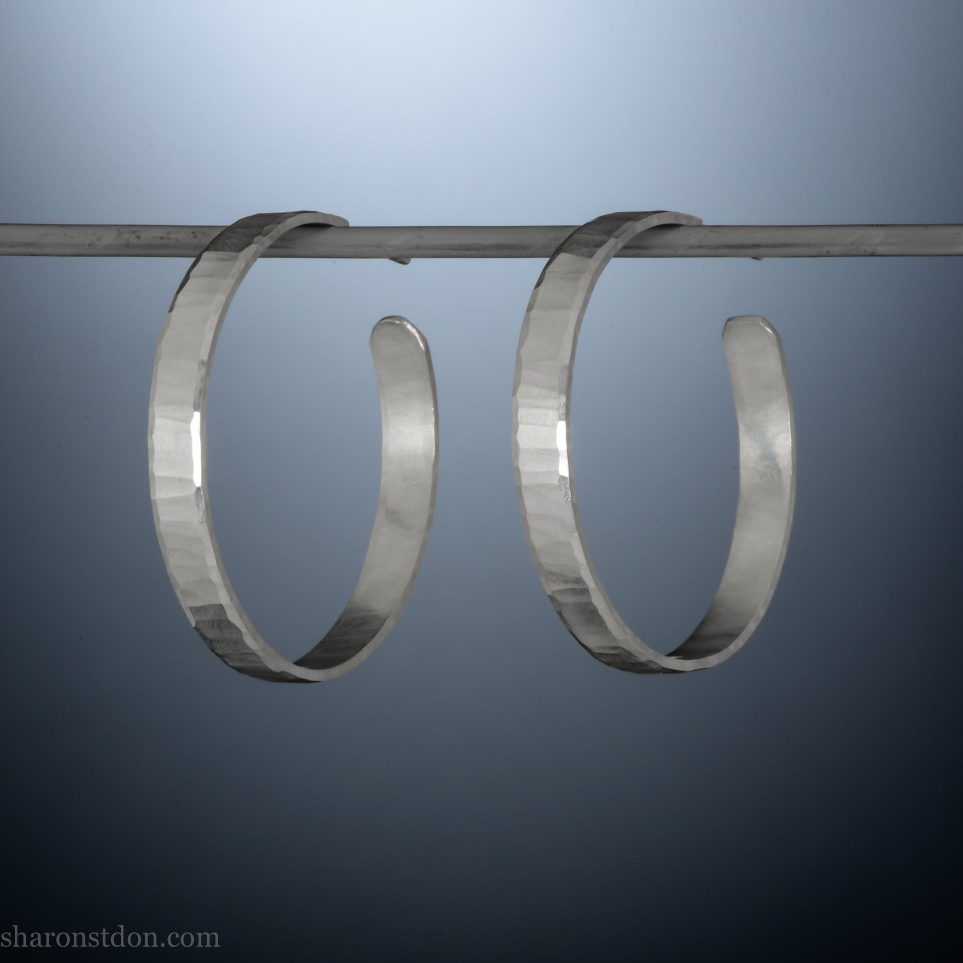 Hand hammered solid sterling silver hoop earrings with faceted, wavy texture and matte satin finish, 30 mm x 4 mm.