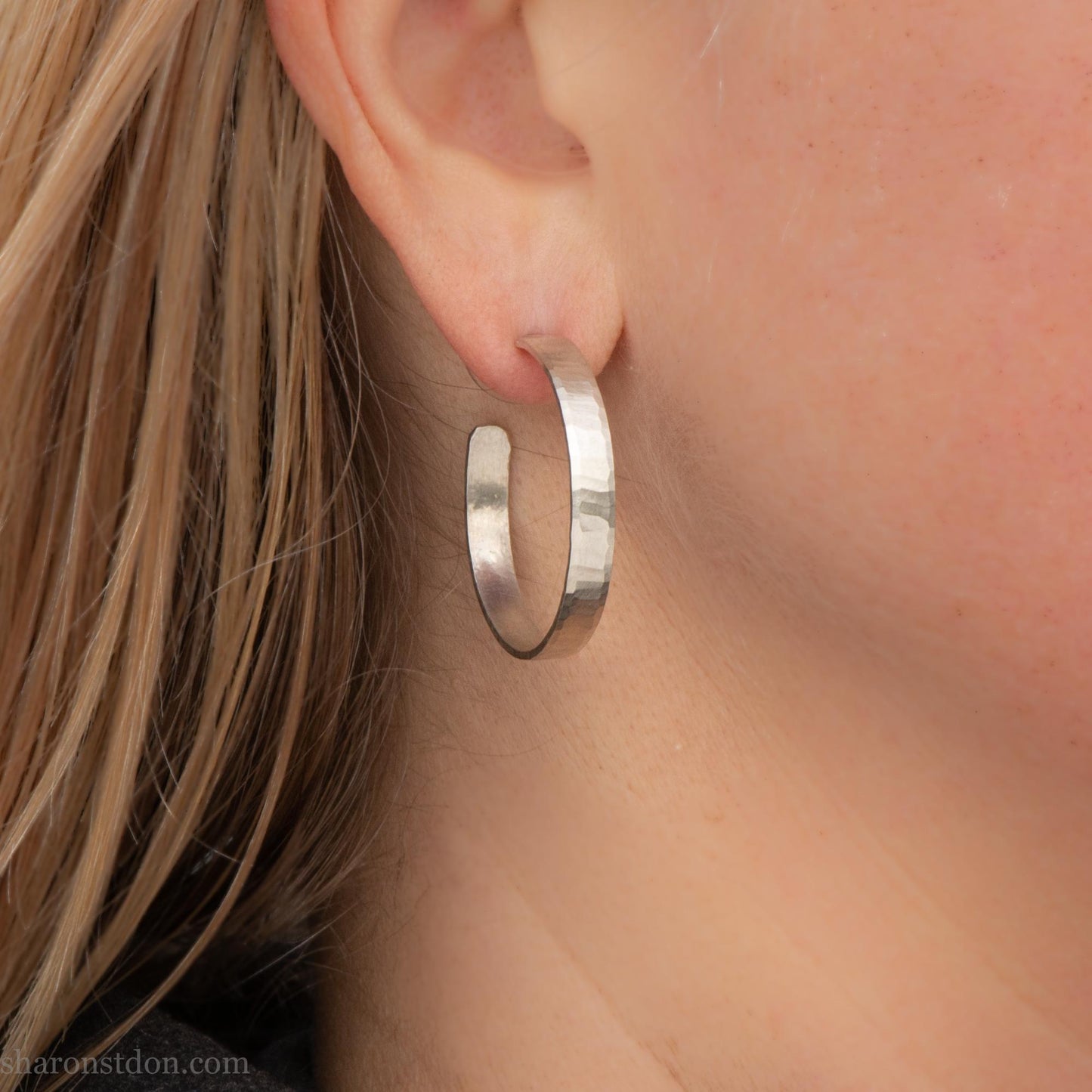 30 mm x 4 mm solid sterling silver hoop earrings, handmade with wavy hammered texture and shiny matte finish, shown on a model with long blonde hair.
