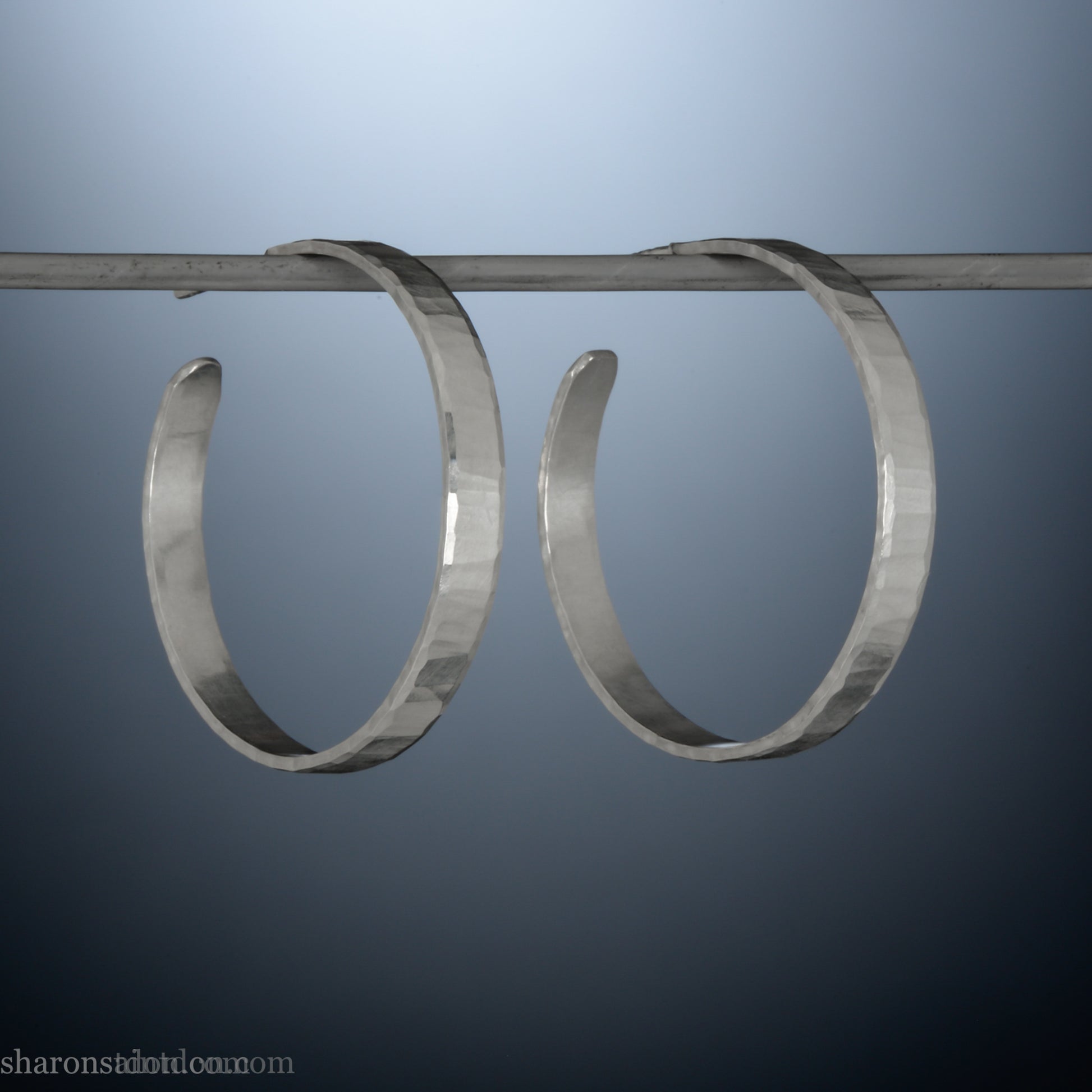 Hand hammered solid sterling silver hoop earrings with faceted, wavy texture and matte satin finish, 30 mm x 4 mm.