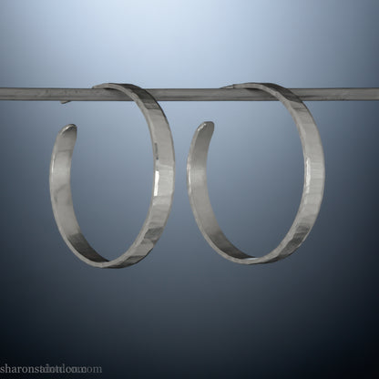 Hand hammered solid sterling silver hoop earrings with faceted, wavy texture and matte satin finish, 30 mm x 4 mm.