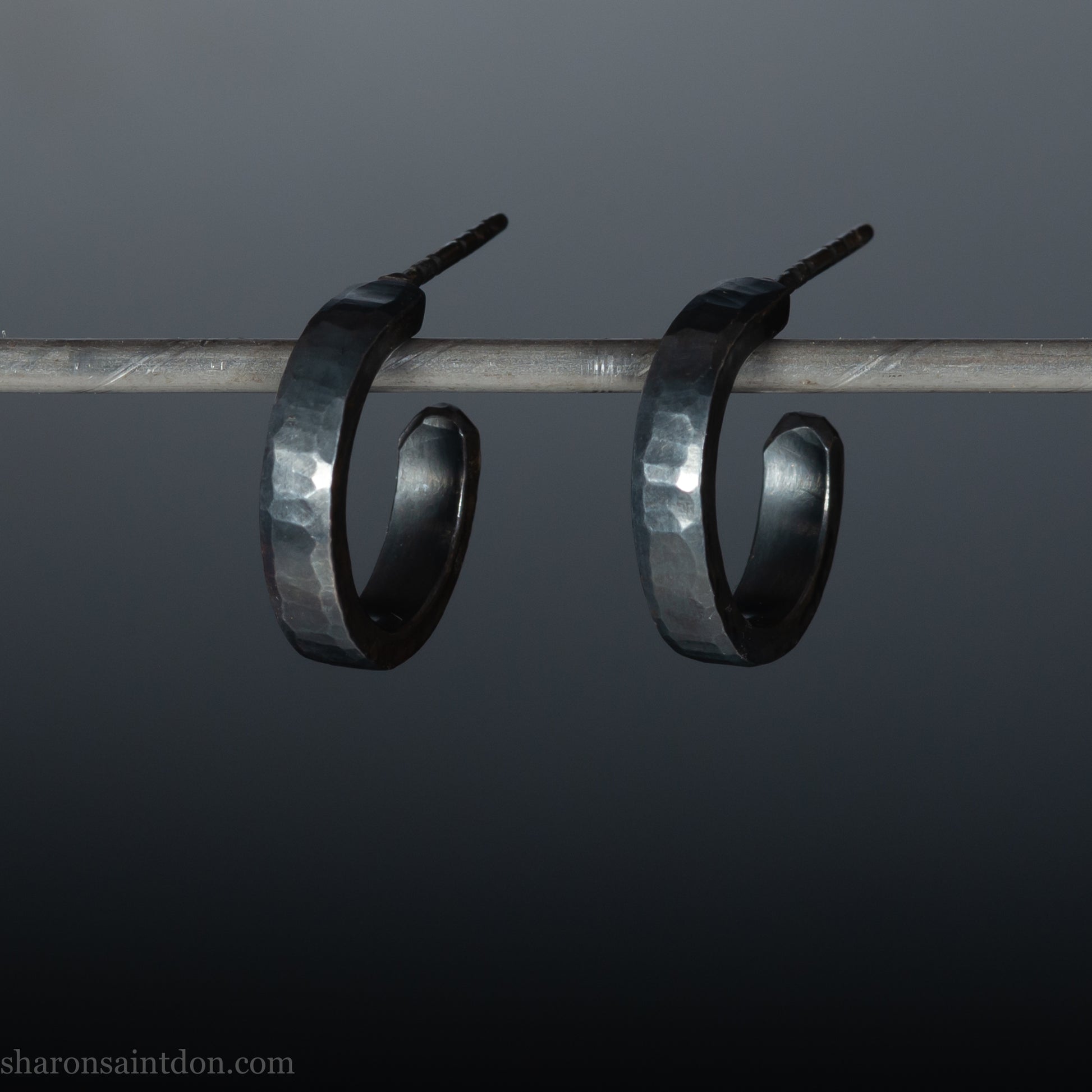 Solid 925 sterling silver hoop earrings with an oxidized, matte, black finish. 18mm exterior diameter, 15mm interior, 3mm wide, and 1.5mm thick. Solid sterling silver posts and backs. Handcrafted in the USA, each pair hand hammered by Sharon Saint Don.