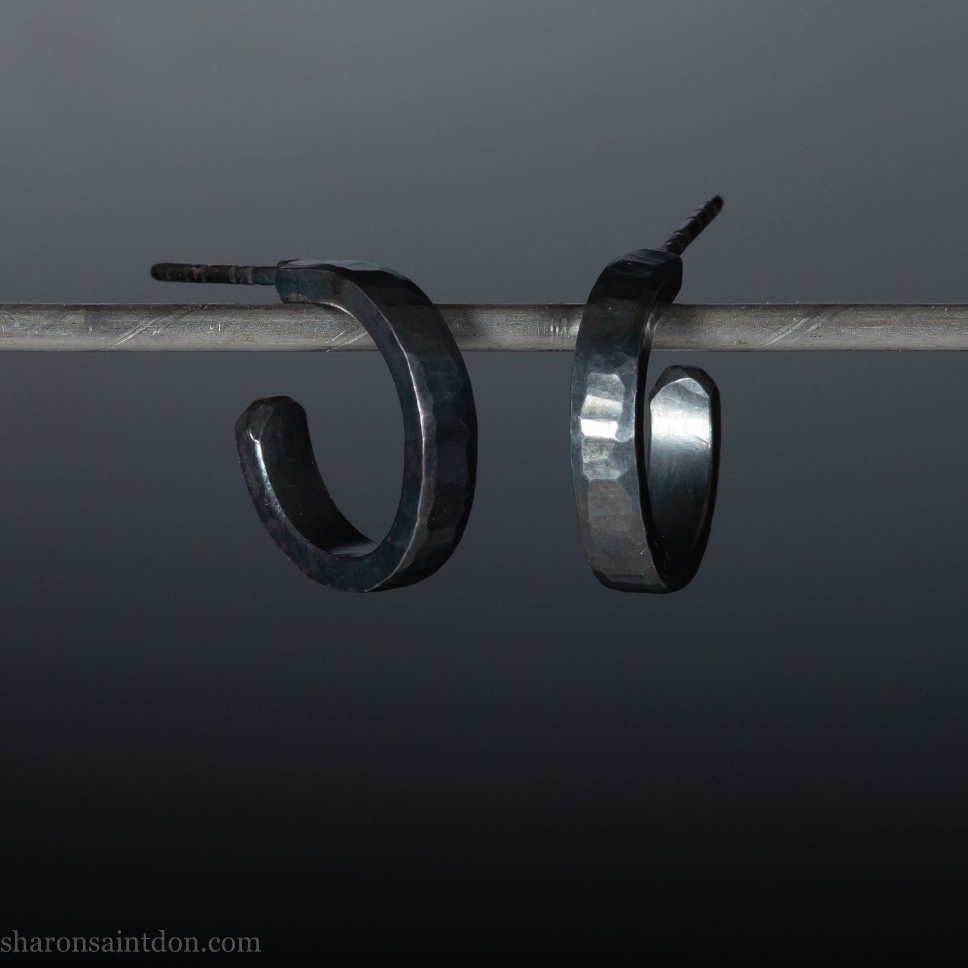 Solid 925 sterling silver hoop earrings with an oxidized, matte, black finish. 18mm exterior diameter, 15mm interior, 3mm wide, and 1.5mm thick. Solid sterling silver posts and backs. Handcrafted in the USA, each pair hand hammered by Sharon Saint Don.