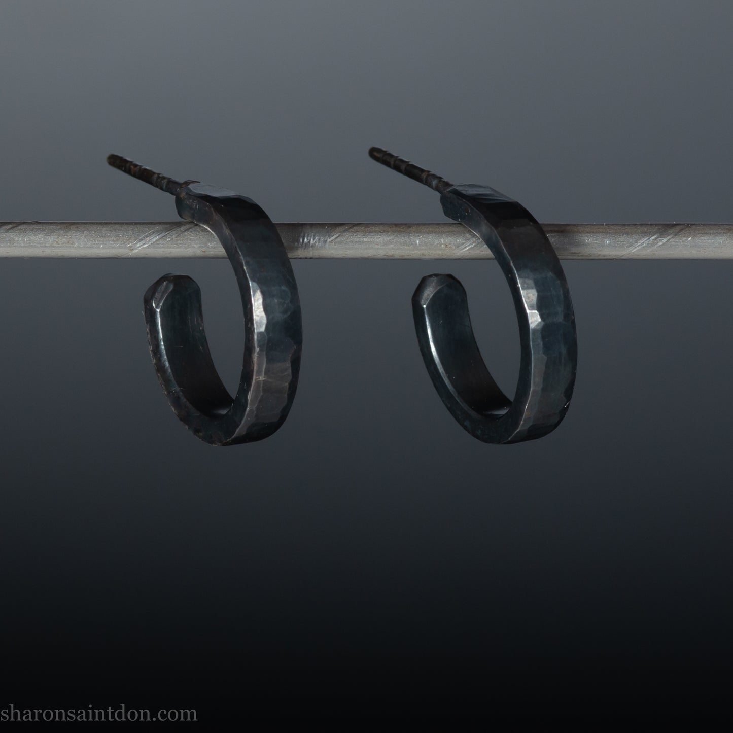 Solid 925 sterling silver hoop earrings with an oxidized, matte, black finish. 18mm exterior diameter, 15mm interior, 3mm wide, and 1.5mm thick. Solid sterling silver posts and backs. Handcrafted in the USA, each pair hand hammered by Sharon Saint Don.