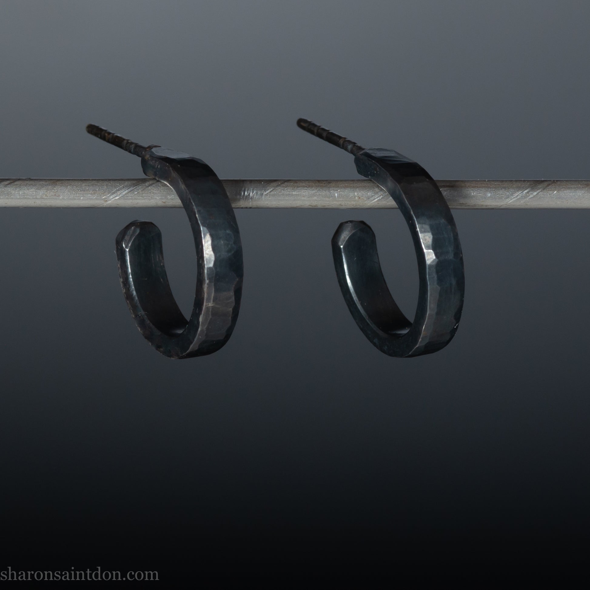 Solid 925 sterling silver hoop earrings with an oxidized, matte, black finish. 18mm exterior diameter, 15mm interior, 3mm wide, and 1.5mm thick. Solid sterling silver posts and backs. Handcrafted in the USA, each pair hand hammered by Sharon Saint Don.