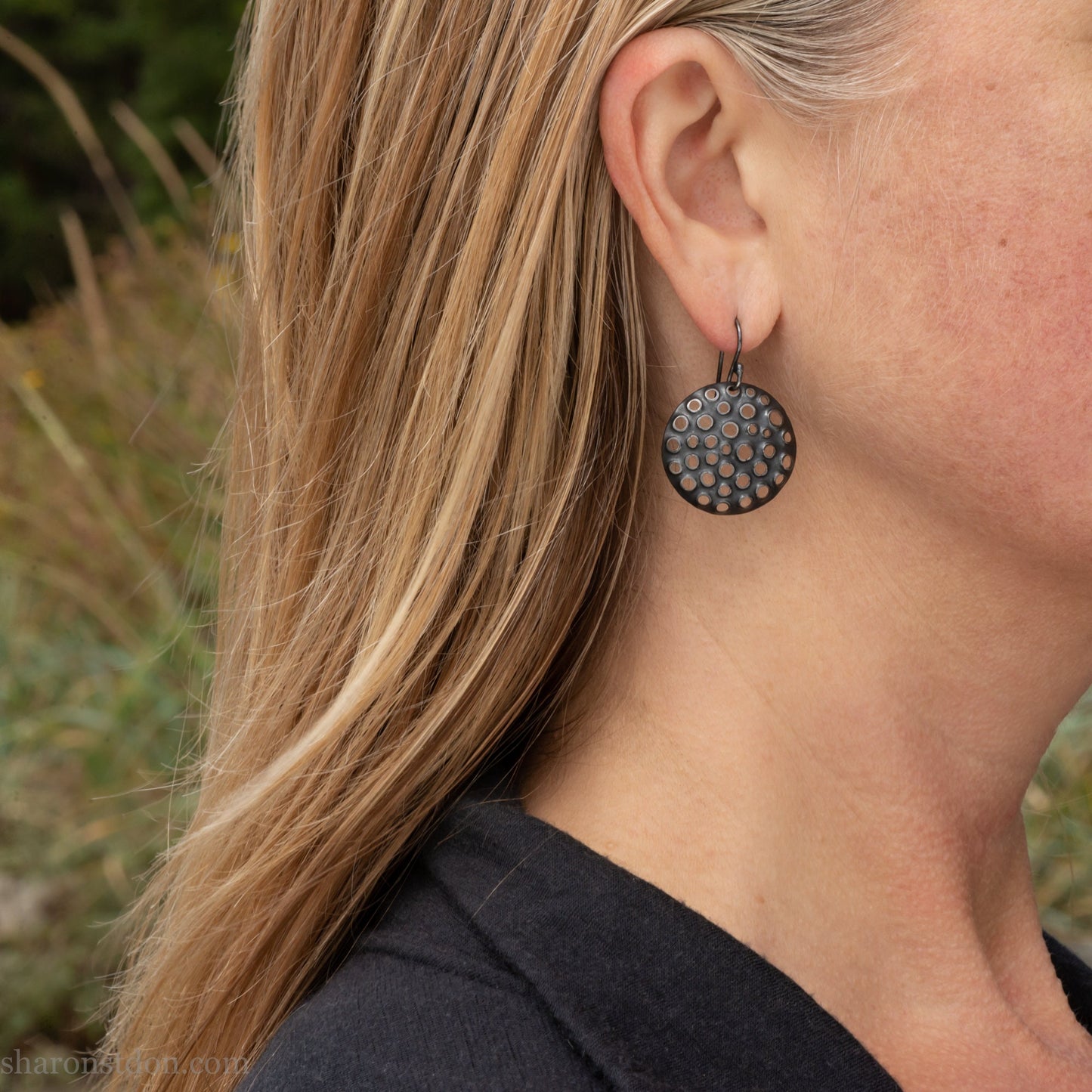 25mm solid 925 sterling silver round disc earrings worn on ear, hand-punched pattern, flat matte black oxidized finish