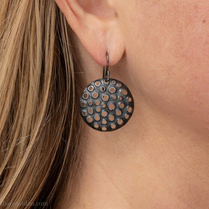 25mm solid 925 sterling silver round disc earrings worn on ear, hand-punched pattern, flat matte black oxidized finish