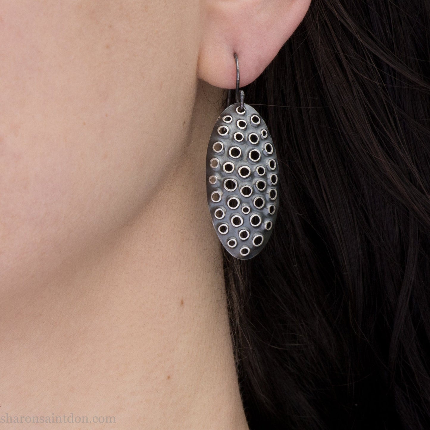 38mm solid 925 sterling silver oval disc earrings worn on ear, hand-punched pattern, dark antique patina with silver highlights.