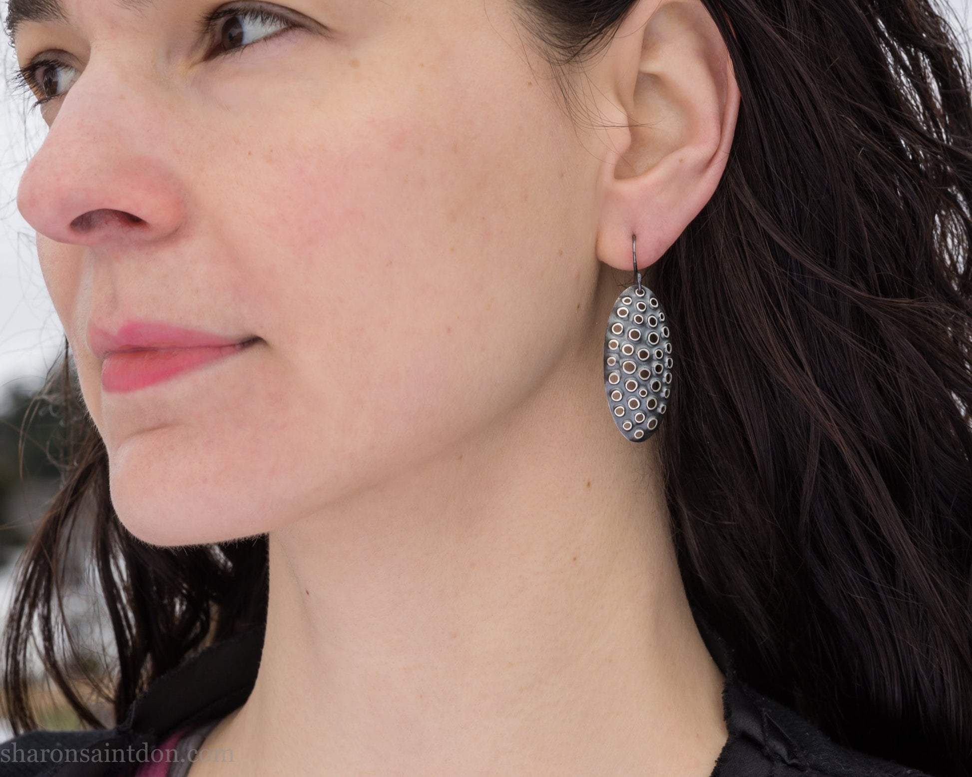 38mm solid 925 sterling silver oval disc earrings worn on ear, hand-punched pattern, dark antique patina with silver highlights.