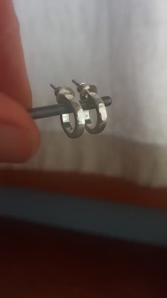 Man with light skin and brown beard wearing handcrafted solid sterling silver hoop earrings, with a hammered texture and a matte, brushed, shiny finish. SIZE: 12mm exterior diameter, 9mm interior, 2mm wide. and 1.5mm thick.