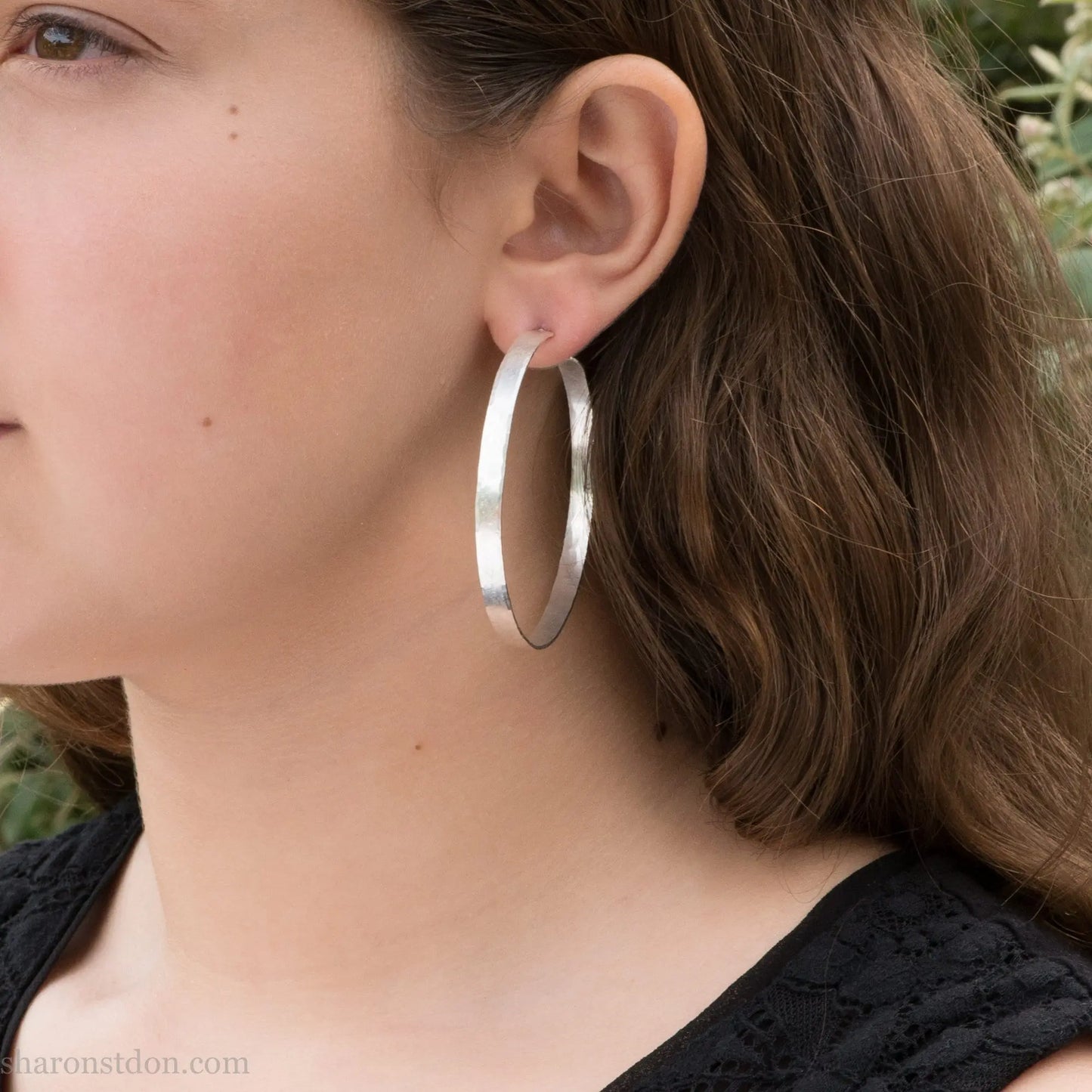55mm sterling silver hoop earrings with hammered texture and matte brushed finish, shown worn on ear.