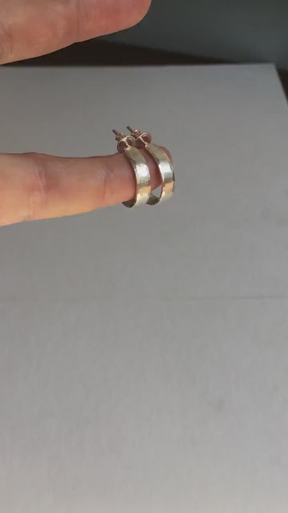 A close-up view of handcrafted solid silver hoop earrings, 18mm diameter with a hammered matte finish.