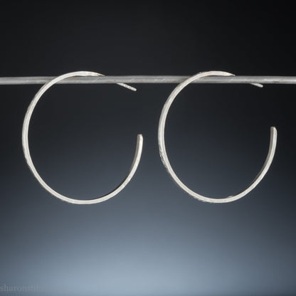 Solid 925 sterling silver hoop earrings. Handmade by Sharon SaintDon in North America. 40mm diameter, 2mm wide, 1.5mm thick, Brushed, matte finish and silver posts and backs.
