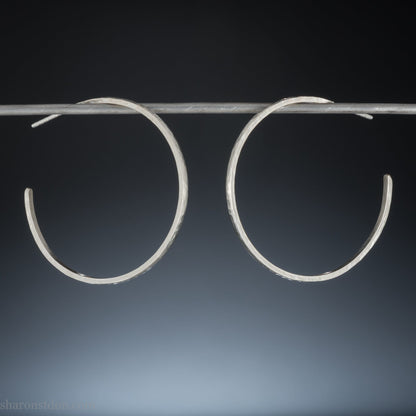 40mm diameter, 2mm wide, handmade 925 sterling silver hoop earrings. Solid 925 sterling silver hoop earrings. Handmade by Sharon SaintDon in North America. 40mm diameter, 2mm wide, 1.5mm thick, Brushed, matte finish and silver posts and backs.