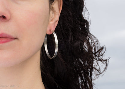 Solid 925 sterling silver hoop earrings. Handmade by Sharon SaintDon in North America. 40mm diameter, 2mm wide, 1.5mm thick, Brushed, matte finish and silver posts and backs.
