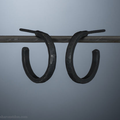 18x2mm oxidized black 925 sterling silver hammered hoop earrings with a matte dark patina, shown on display bar.