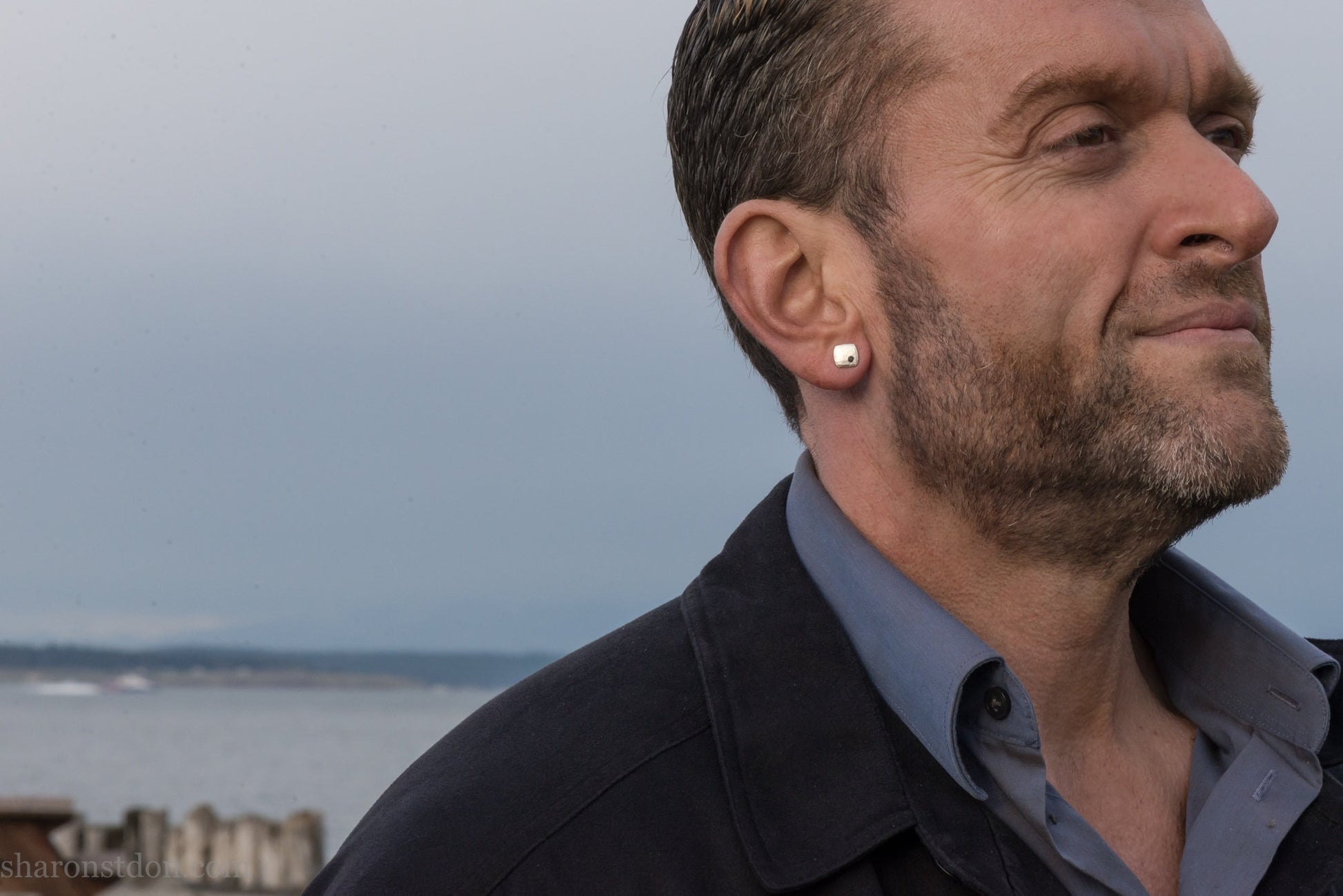 Black spinel stud earrings in sterling silver, 7mm square with matte finish, worn on a human ear.