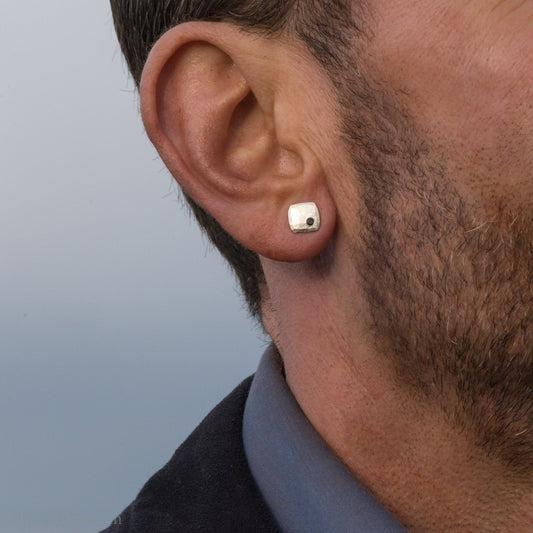 Black spinel stud earrings in sterling silver, 7mm square with matte finish, worn on a human ear.