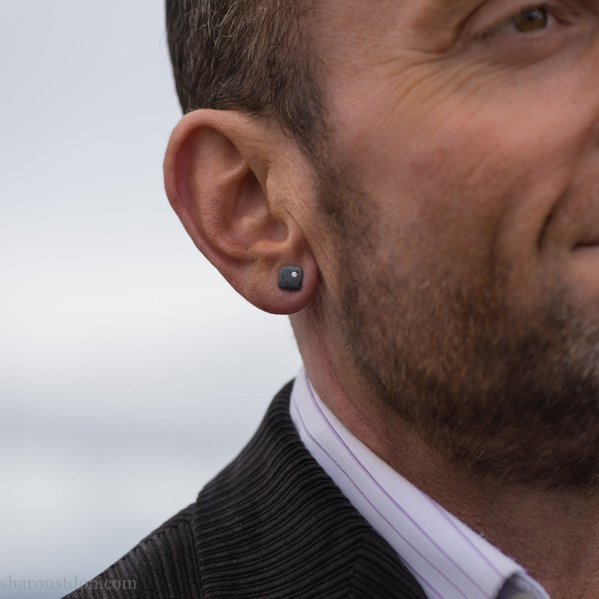 Man wearing Canadian diamond 7mm square stud earrings, oxidized black 925 sterling silver.