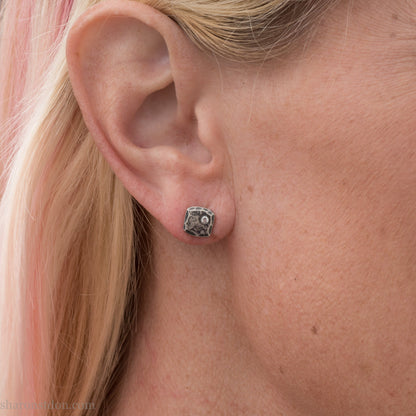 7mm square 925 sterling silver stud earrings with an imitation diamond gemstone in the corner. Hammered texture with an antiqued, oxidized black finish rubbed back to show the texture. Handmade by Sharon SaintDon in North America for men or women.