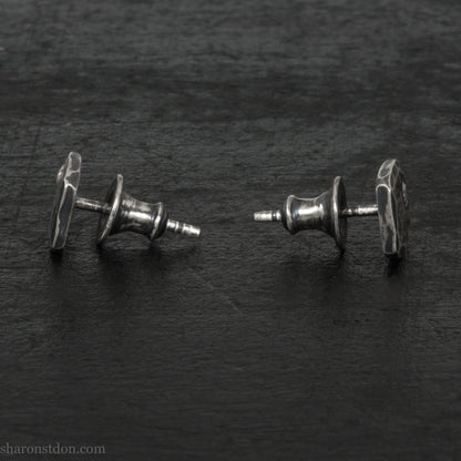 7mm square 925 sterling silver stud earrings with an imitation diamond gemstone in the corner. Hammered texture with an antiqued, oxidized black finish rubbed back to show the texture. Handmade by Sharon SaintDon in North America for men or women.
