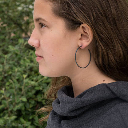 Handmade 925 sterling silver hoop earrings.  Oxidized black, narrow, Solid 925 sterling silver hoop earrings. Oxidized black, 50mm diameter, 2mm wide, 1.5mm thick. Lightweight hammered large hoop earrings handmade by Sharon SaintDon in North America.