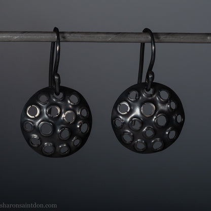15mm round 925 sterling silver disc earrings with mesh perforated holes. Handmade solid oxidized black silver dangle earrings by Sharon SaintDon in North America with hand made black silver french ear hooks.