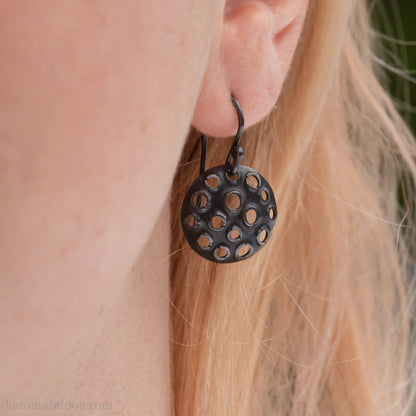 15mm round 925 sterling silver disc earrings with mesh perforated holes. Handmade solid oxidized black silver dangle earrings by Sharon SaintDon in North America with hand made black silver french ear hooks.