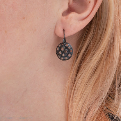 15mm round 925 sterling silver disc earrings with mesh perforated holes. Handmade solid oxidized black silver dangle earrings by Sharon SaintDon in North America with hand made black silver french ear hooks.