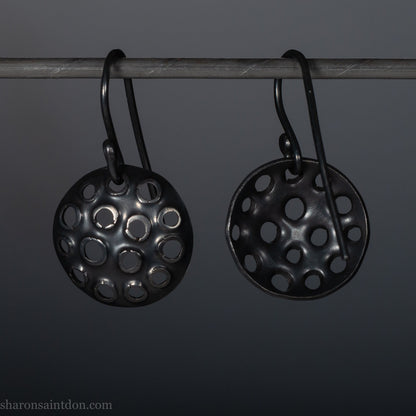 15mm round 925 sterling silver disc earrings with mesh perforated holes. Handmade solid oxidized black silver dangle earrings by Sharon SaintDon in North America with hand made black silver french ear hooks.