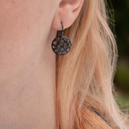 15mm round 925 sterling silver disc earrings with mesh perforated holes. Handmade solid oxidized black silver dangle earrings by Sharon SaintDon in North America with hand made black silver french ear hooks.
