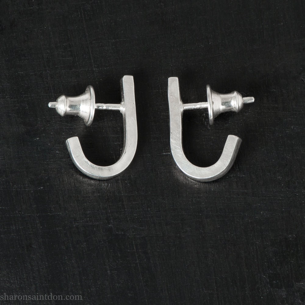 J shaped wrap earrings handmade from solid 925 sterling silver by Sharon SaintDon in the Pacific Northwest of North America. Size is 17mm high and 2mm wide and thick square wire, wrapping around the bottom of ear, with silver posts and backs. Hand hammered with a matte, shiny, brushed finish.