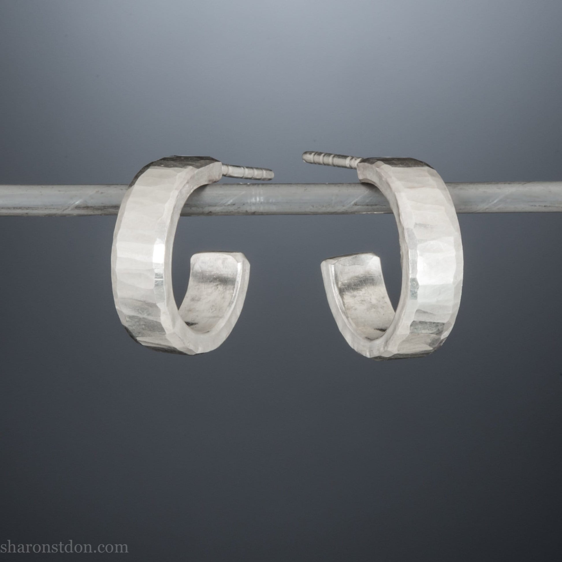 14mm x 4mm small sterling silver hoop earrings, Handmade in North America by Sharon SaintDon. Shiny, hammered texture, solid silver with silver posts and backs for men or women.