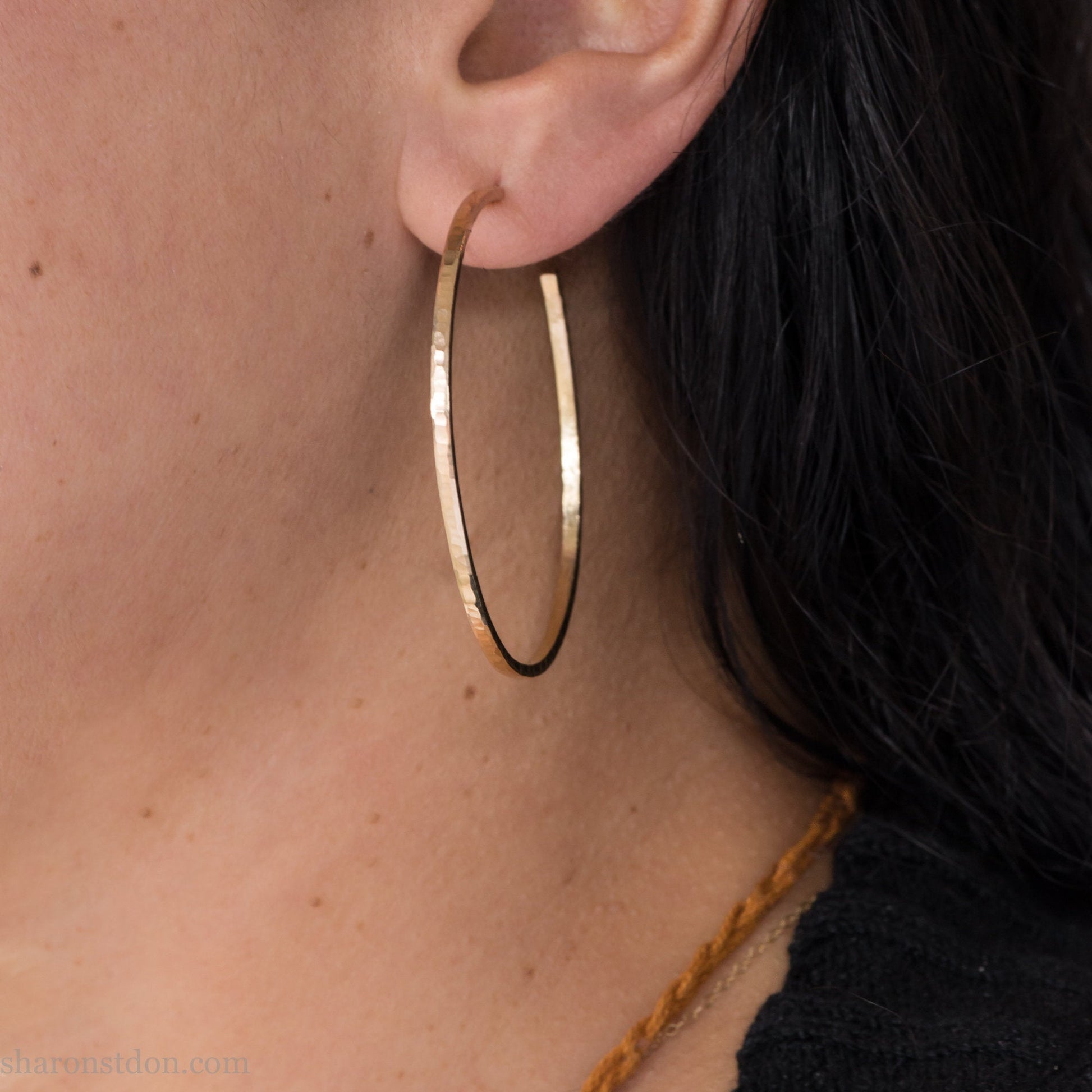 Gold hoop earrings handmade from solid yellow gold in the USA for women. Size large, 50mm diameter, hammered texture.
