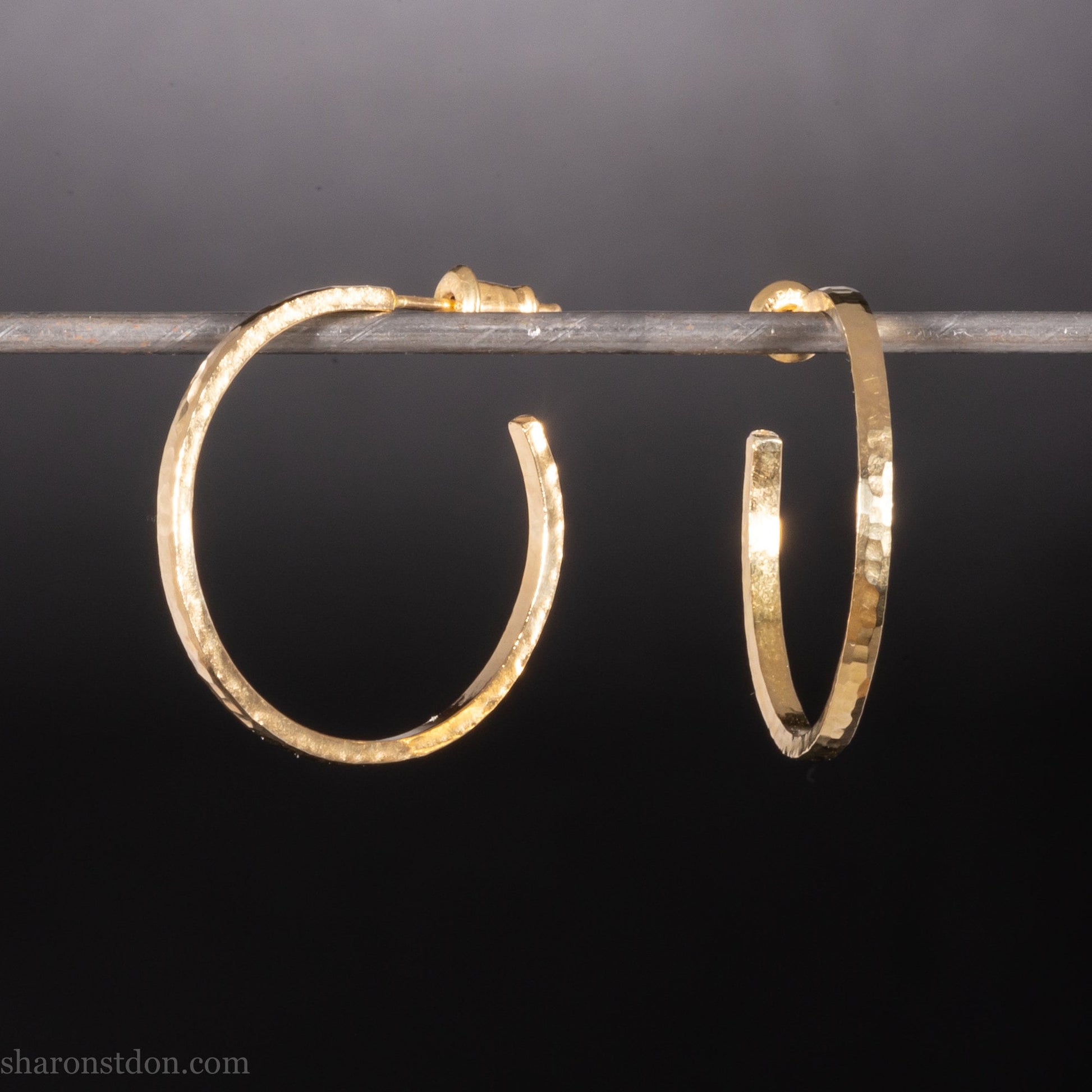 25mm diameter by 1.5mm thick handmade solid 14k yellow gold hoop earrings with solid 14k gold posts and backs. Handmade by Sharon SaintDon in North America. Hammered from solid gold with a matte finish.
