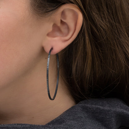 Handmade 925 sterling silver hoop earrings for women. 55mm diameter, 2mm wide, oxidized black, large hoops for daily wear. Minimalist, comfortable, lightweight with a hammered, texture.