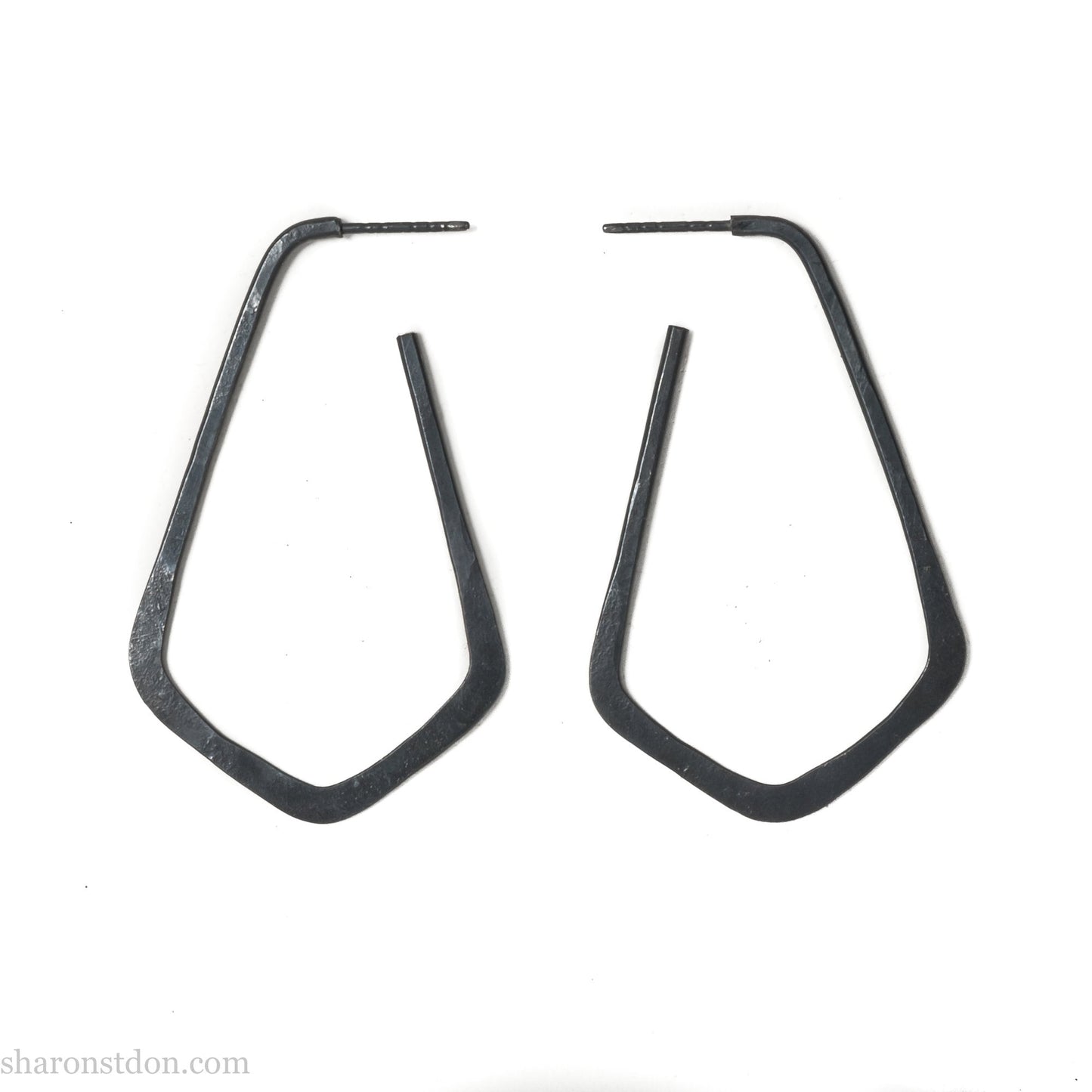 925 sterling silver hoop earrings handmade in North America by Sharon SaintDon. Long, angular, teardrop shape with three points at bottom, oxidized black with hammered texture. SIZE: 5cm high x 32mm wide