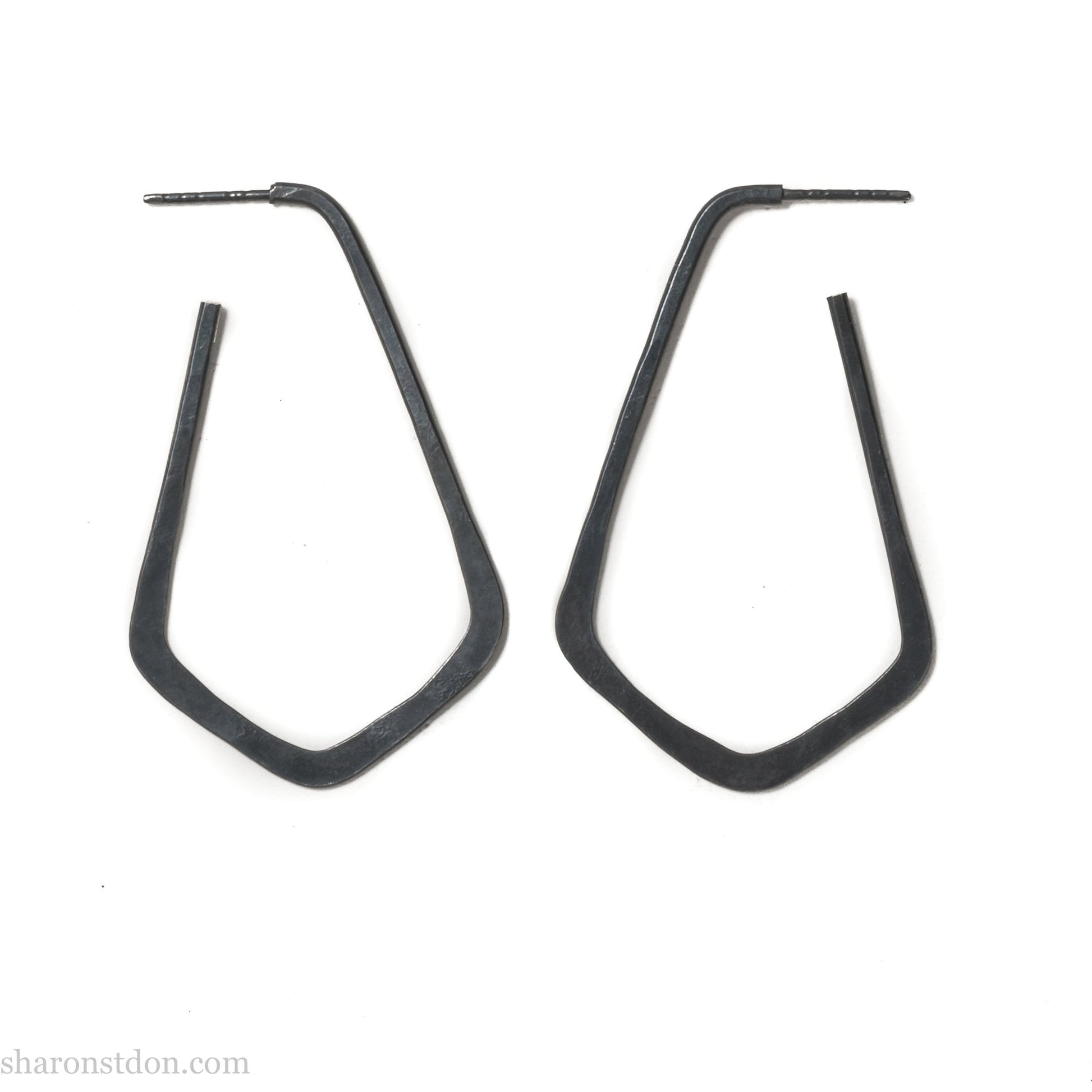 925 sterling silver hoop earrings handmade in North America by Sharon SaintDon. Long, angular, teardrop shape with three points at bottom, oxidized black with hammered texture. SIZE: 5cm high x 32mm wide