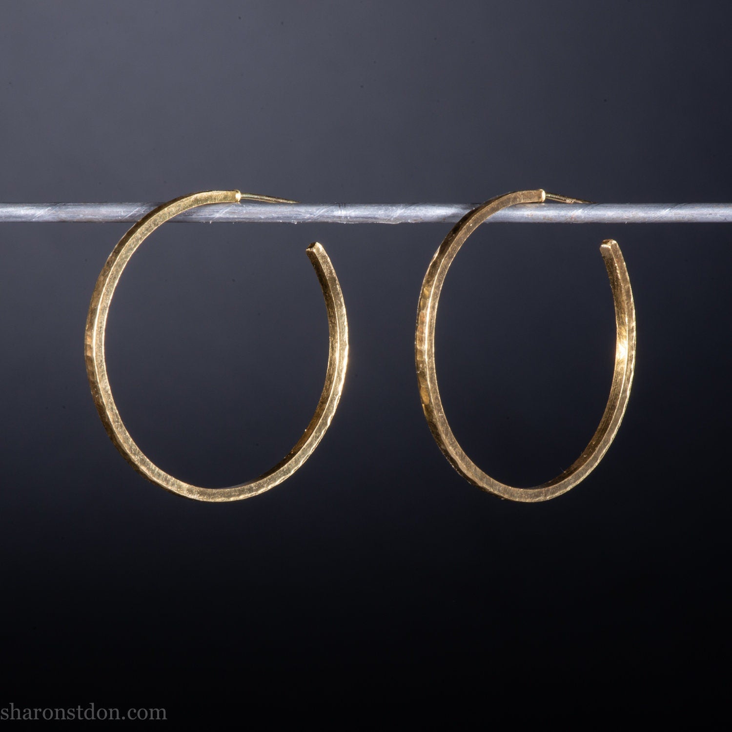 30mm diameter by 1.5mm thick handmade solid 14k yellow gold hoop earrings. Handmade by Sharon SaintDon in North America. Hammered from solid gold with a matte finish.