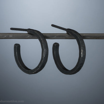 18mm x 2mm oxidized black 925 sterling silver hoop earrings for men. Hammered texture, matte, flat black handmade by Sharon SaintDon in North America.