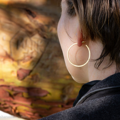 Solid 18k yellow gold hoop earrings set, handmade in North America by Sharon SaintDon.30mm diameter round, 2mm wide, 1.5mm thick, with hammered texture and matte finish.