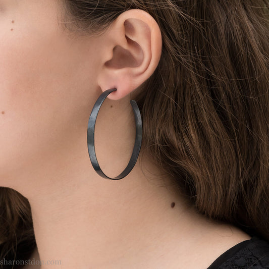 Handmade 925 sterling silver hoop earrings for women. 55mm diameter, 5mm wide, Oxidized black, large hoops for daily wear. Minimalist, comfortable, lightweight with a hammered, texture.