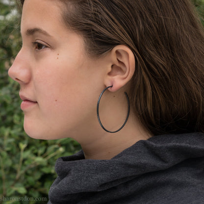 Handmade 925 sterling silver hoop earrings for women. 55mm diameter, 2mm wide, oxidized black, large hoops for daily wear. Minimalist, comfortable, lightweight with a hammered, texture.