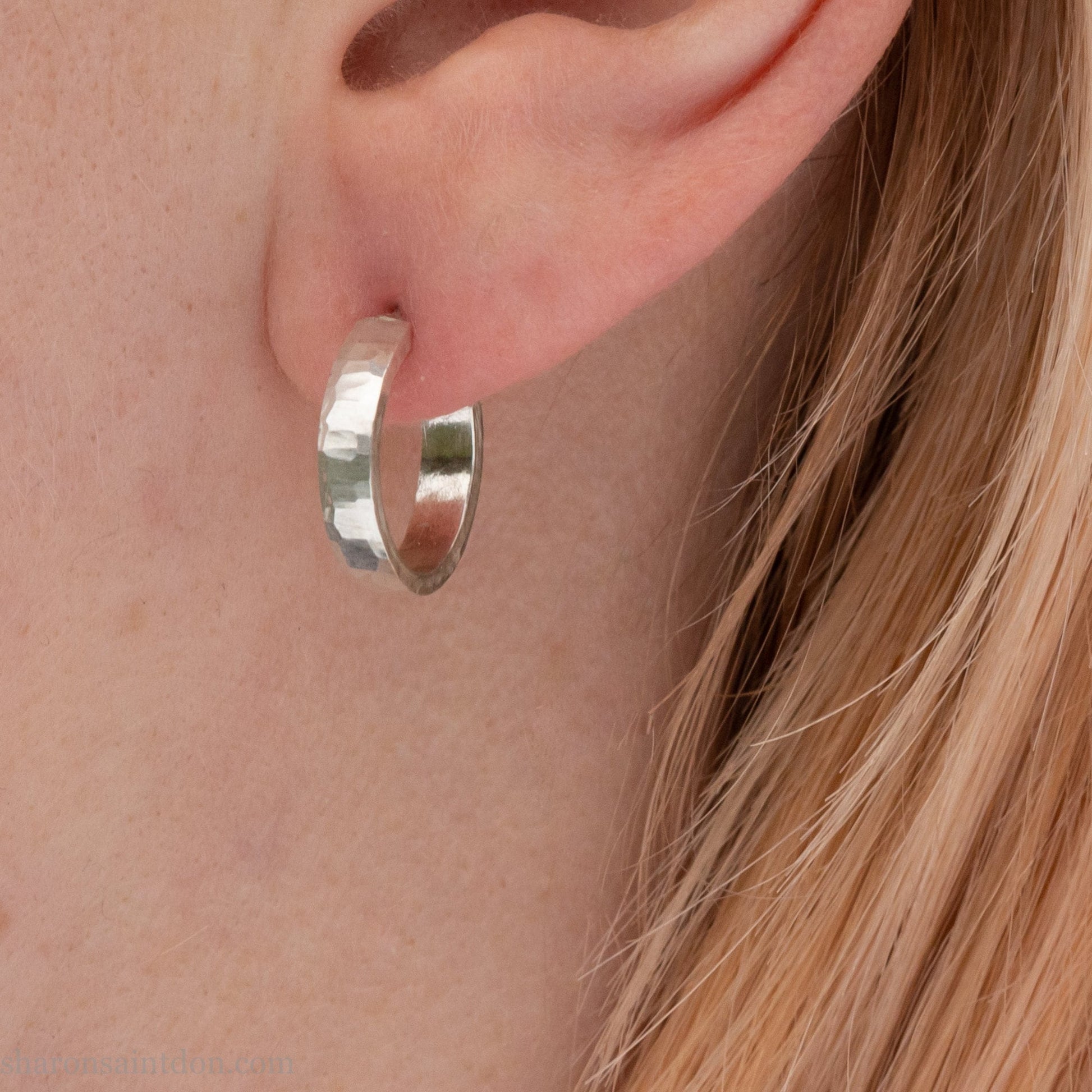 14mm x 3mm small sterling silver hoop earrings. Handmade in North America by Sharon SaintDon. Hammered solid silver with silver posts and backs.