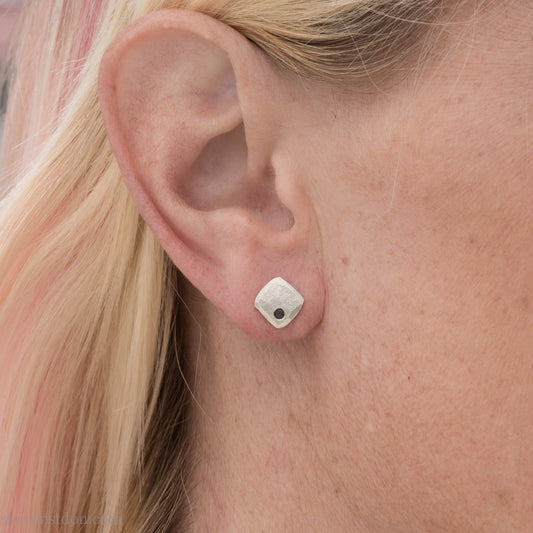 7mm square 925 sterling silver stud earrings with a black spinel gemstone in the corner. Hammered texture with a matte, brushed, shiny finish. Handmade by Sharon SaintDon in North America for men or women.
