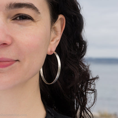 Woman wearing large hammered solid sterling silver hoop earrings 55mm diameter 5mm wide
