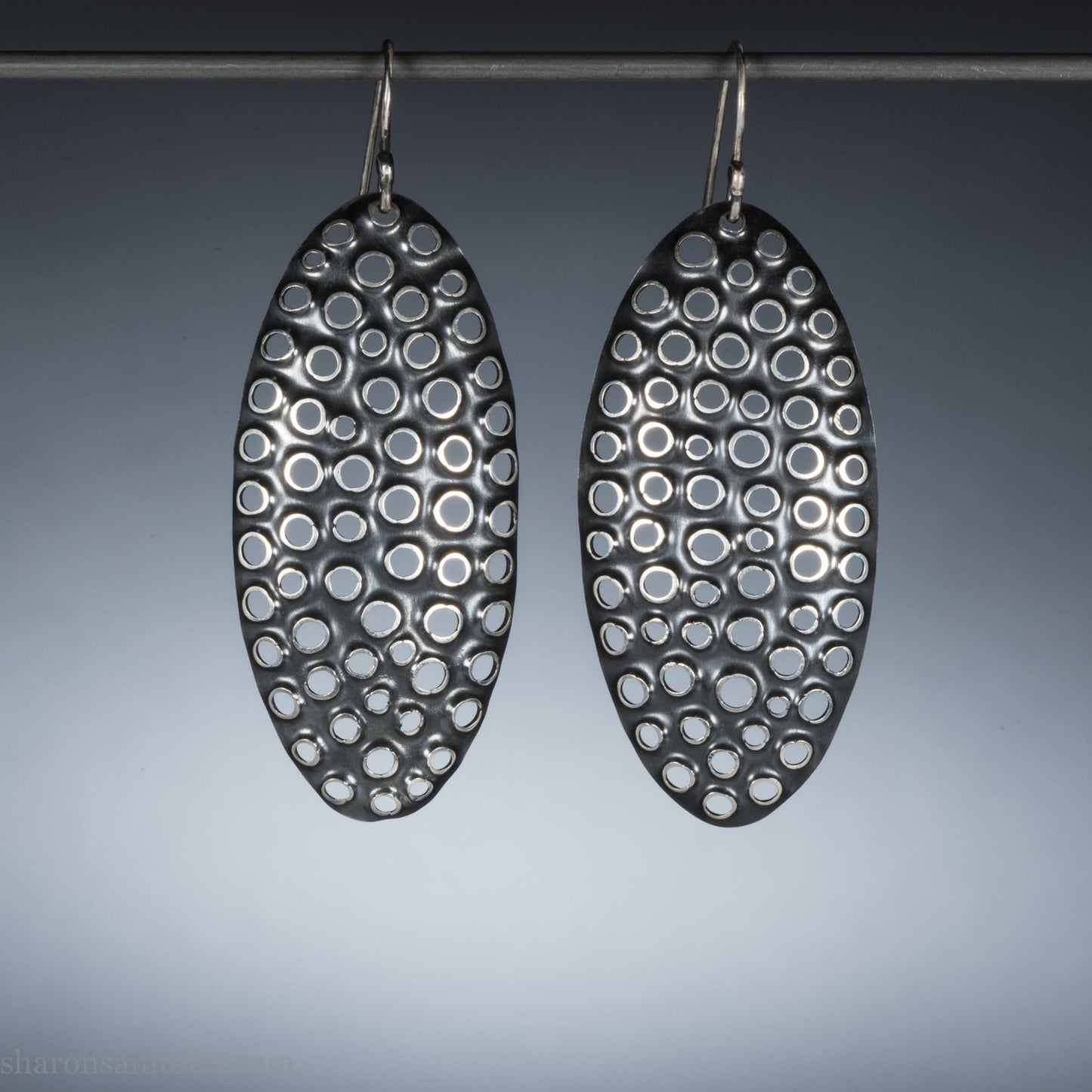Large oval sterling silver dangle earrings with hand-punched detailed holes and antiqued finish.