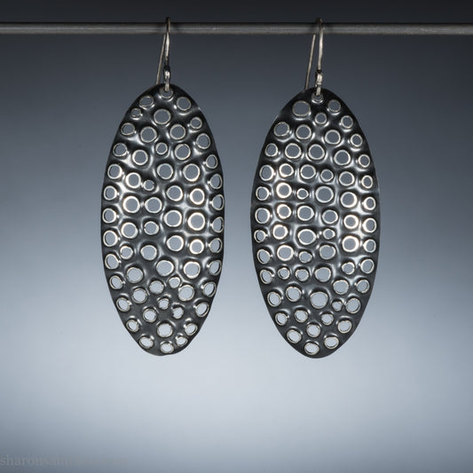 Large oval sterling silver dangle earrings with hand-punched detailed holes and antiqued finish.