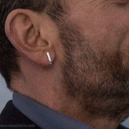Men's solid 925 sterling silver J wrap huggie hoop earrings, matte finish, handcrafted. Worn on ear of man with beard.
