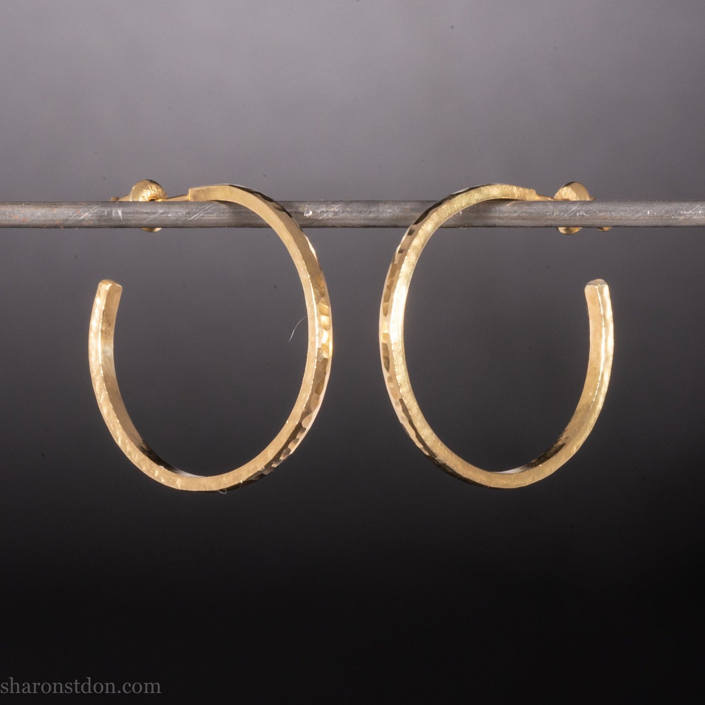 25mm solid yellow gold hoop earrings with hammered matte finish and solid gold posts, handmade by Sharon SaintDon.